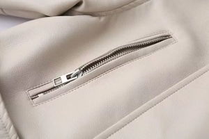 Close-up of silver metal zipper and fine leather texture on a beige biker jacket