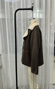 Detail of a brown faux suede jacket featuring thick cream fleece lining and large side pockets