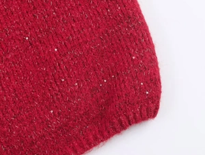 Macro shot of red knit cardigan hem featuring silver sequins and ribbed texture