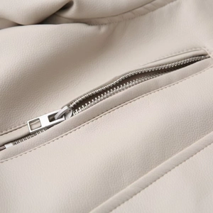 Detailed close-up of cream faux leather texture and silver metal zipper on motorcycle jacket
