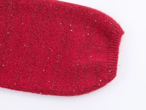 Close-up of red knit fabric with silver sequins and ribbed cuff texture details
