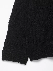 Close-up of black hollow-out crochet knit pattern with side slit details on cardigan