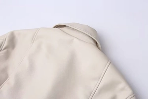 Detailed close-up of cream faux leather collar and shoulder seams of a motor jacket