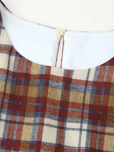 Gros plan du décolleté de robe à carreaux vintage avec col blanc et bouton