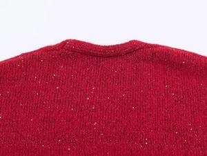 Detail shot of a red knitted cardigan featuring festive sparkling silver sequins and soft texture