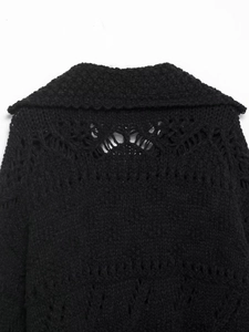 Close-up of wavy collar and hollow geometric knit patterns on a black cardigan