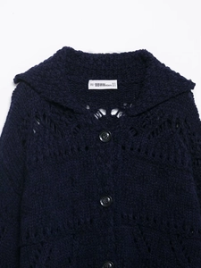 Detail of navy crochet knit cardigan featuring lapel collar and dark round buttons