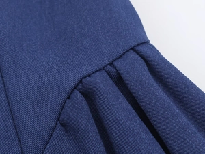 Détail rapproché du tissu tissé bleu marine plissé montrant les coutures de la robe