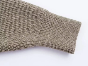 Détail des poignets en tricot marron avec des fils métalliques dorés décoratifs