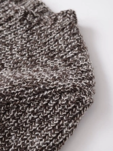 Close-up of brown and beige chunky knit fabric texture showing intricate weave patterns