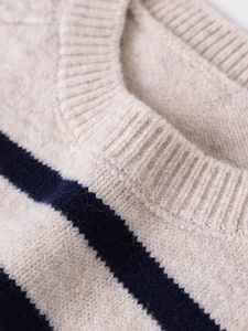 Detail shot of ribbed neckline and navy stripes on a beige knitted sweater