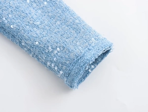 Detail shot of light blue tweed fabric featuring intricate sequins and woven texture