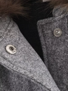 Gros plan sur la veste en laine grise avec col en fourrure et boutons pressions