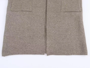 Gros plan d'un gilet en tricot taupe montrant des poches côtelées et une texture laine