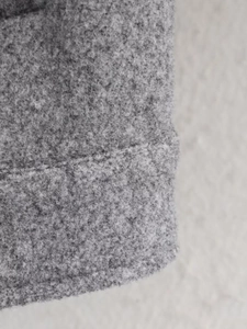 Détail du tissu gris de la veste baseball avec coutures précises et texture de laine