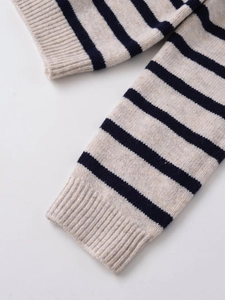 Detailed close-up of ribbed cuffs and striped knit pattern on the beige wool blend sweater