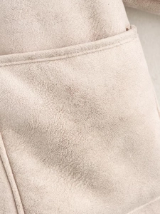 Detailed macro view of beige faux shearling fabric and precision stitching on the jacket