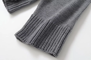 Close-up of dark grey knit sweater showing high-quality ribbed cuffs and hem texture