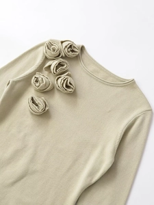 Detail of 3D knit rose embellishments on a sage green slim-fit knit sweater