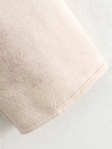 Close-up of beige suede fabric showing fine frosted texture and precise stitching detail