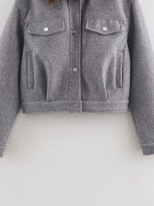 Détail d'une veste baseball grise en laine avec boutons-pression et texture