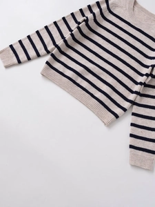 Detailed view of the ribbed knit texture and classic navy stripes on a beige sweater