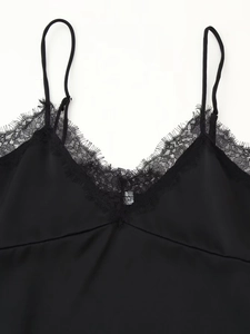 Detailed close-up of V-neck lace trim and silky satin fabric on the black camisole top