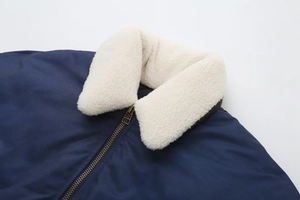 Detail of warm faux sheepskin collar and durable gold metal zipper on navy winter jacket