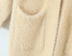Detailaufnahme einer beigefarbenen Mohair-Strickjacke mit flauschiger Struktur und Tasche