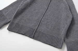 Detail of grey knitted sweater showing high-quality rib-knit hem and thick vertical texture