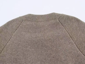 Détail du col d'un pull en maille marron avec des coutures de manches raglan fines