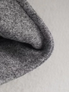 Gros plan sur la texture du tissu polaire gris avec ourlet cousu sur une veste thermique