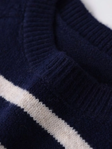 Close-up of ribbed crew neck and textured striped knit fabric on a blue and beige sweater