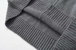 Macro view of dark grey knit sweater showing fine ribbed cuffs and soft fabric texture