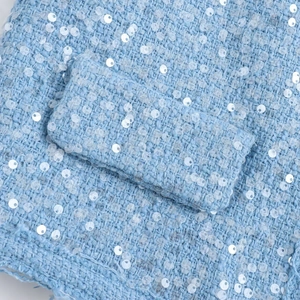 Light blue tweed jacket featuring delicate sequins and woven pocket detail in macro view