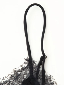 Close-up of black eyelash lace trim and thin shoulder straps with silver rings