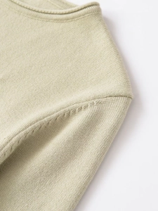 Macro shot of sage green knit sweater neckline and shoulder seam stitching details