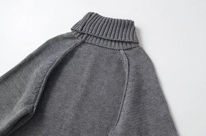 Close-up of thick dark grey knit sweater showing high turtleneck and detailed texture