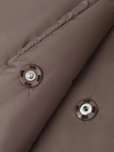 Detailed macro view of dark brown winter jacket featuring durable silver snap buttons