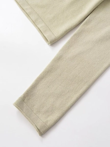 Detail of light sage green knit sweater showing ribbed cuffs and fine fabric texture