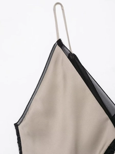 Détail du tissu en satin champagne avec dentelle noire délicate et fine bretelle de robe