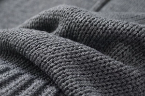 Detailed view of dark grey chunky knit fabric texture on a loose standing collar sweater