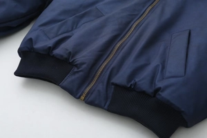 Detail of dark blue bomber jacket with gold metal zipper and ribbed hem texture