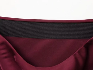 Detail of high elastic black waistband on dark red satin midi skirt with premium stitching