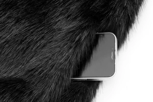 Close-up of fluffy faux fur vest showing side pocket functionality with a mobile phone