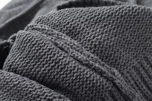 Macro shot of dark grey knit fabric with detailed wave and cable stitch patterns