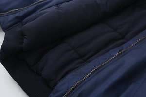 Detail of quilted inner lining, navy blue ribbed cuffs and golden metal zipper