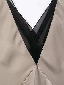 Détail de l'encolure en V élégante avec résille noire sur tissu satiné couleur champagne