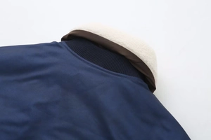 Detail of navy blue coat showing white faux shearling collar and ribbed knit lining texture