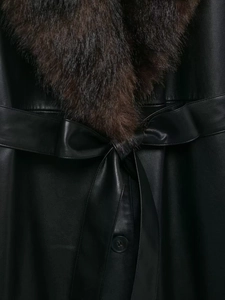 Détail du manteau en similicuir noir avec col en fourrure amovible et ceinture à la taille